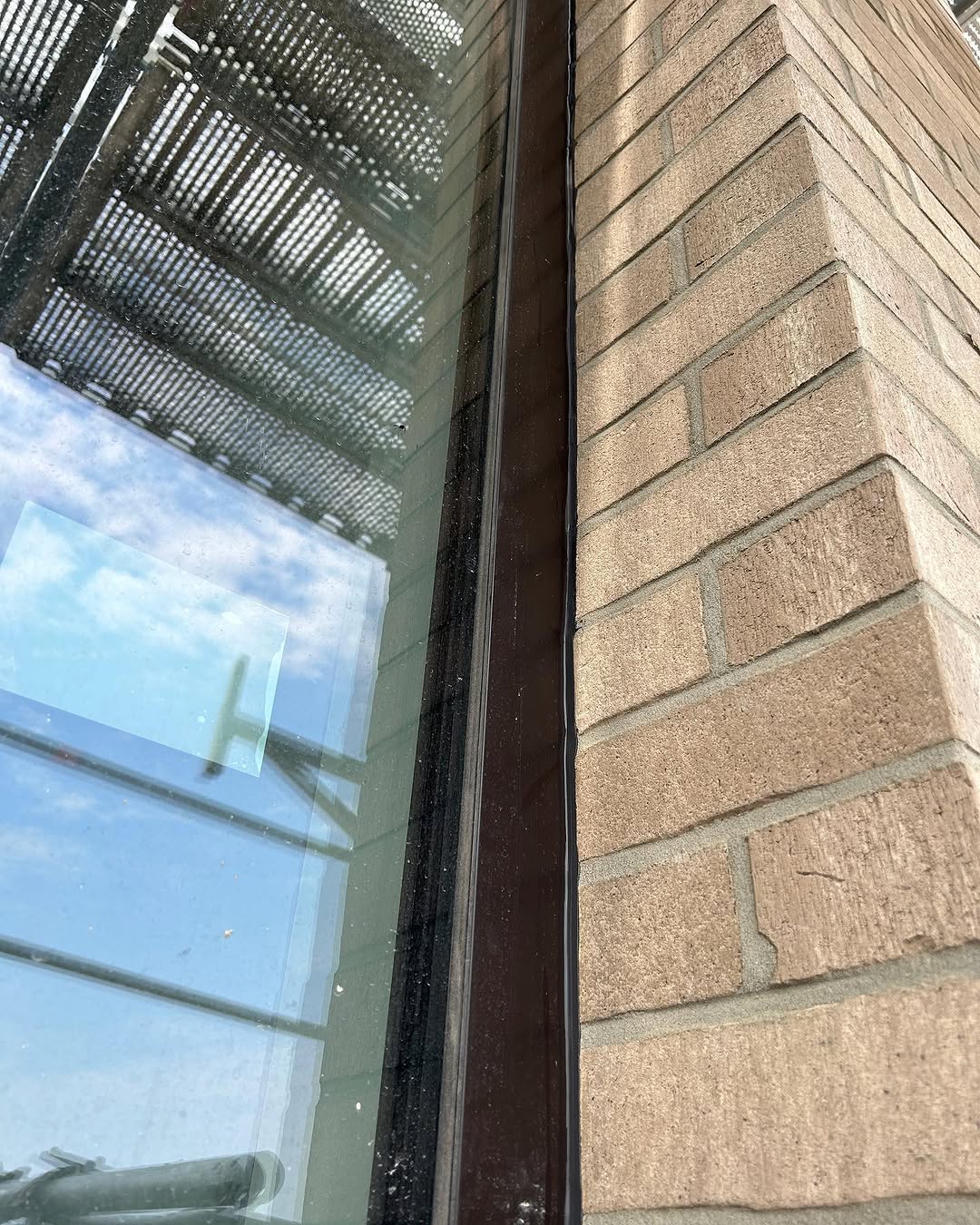 Nahaufnahme der Versiegelung zwischen Fensterrahmen und Klinkermauerwerk